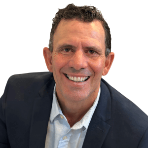 Man smiling in a suit jacket and shirt against a white background.