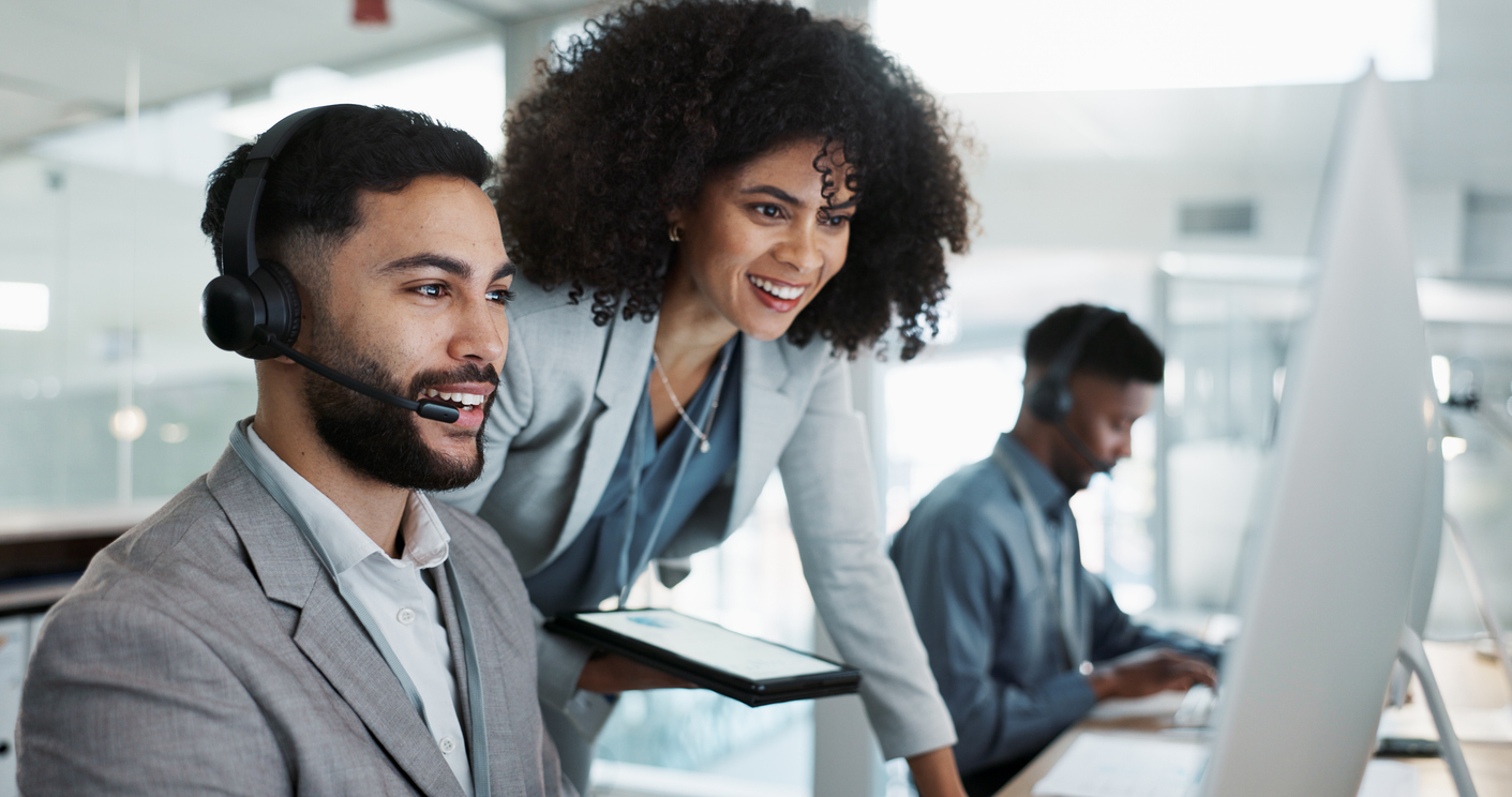 Customer service team collaborating in a modern office with headsets and computers.