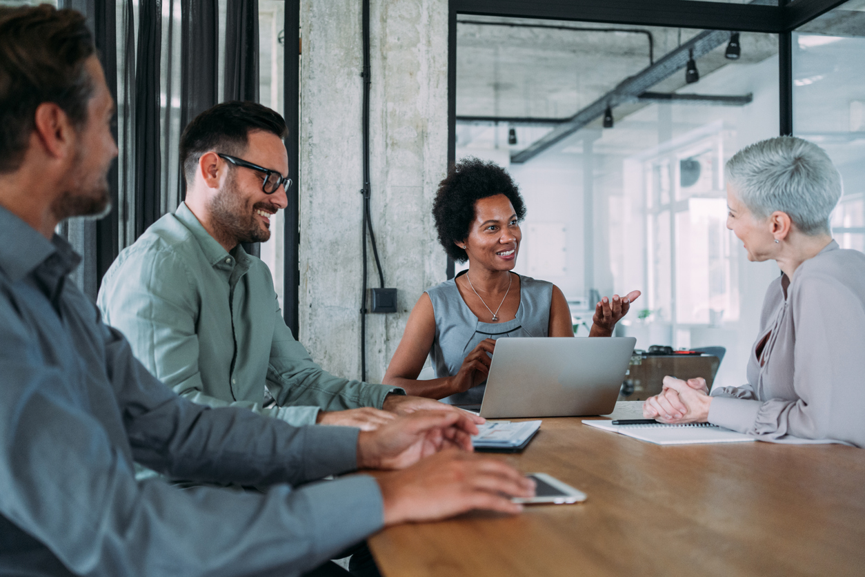 A diverse team having a meeting around a table with a laptop and documents.